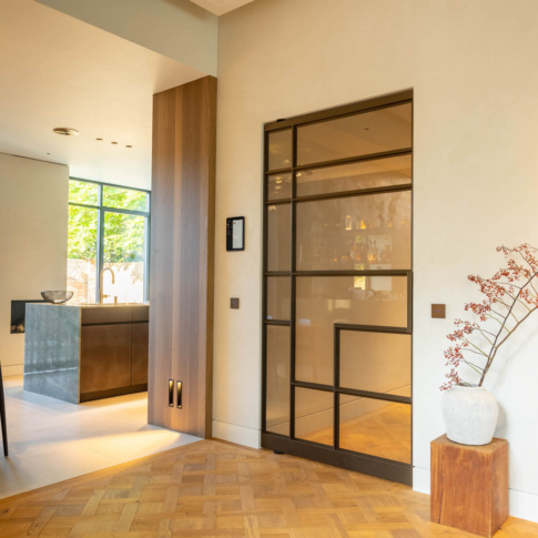 Anodic Brown stalen schuifdeur met glas in een warm interieur met parketvloer en houten accenten.